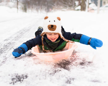 Child sledding on snow covered field