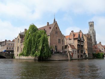 Buildings by river against sky