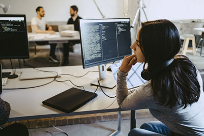 Female hacker looking at computer while working in startup company
