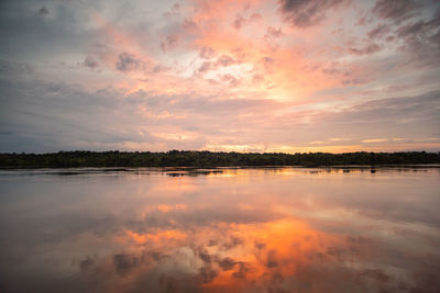 Scenic view of lake against dramatic sky during sunset