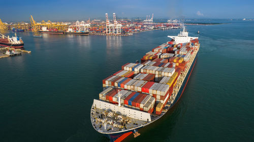 Aerial in front of smart cargo ship carrying container and running 