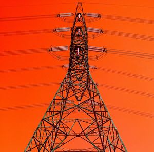 Low angel view of electricity pylon against clear sky during sunset