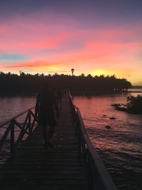 Pier over lake against sky during sunset