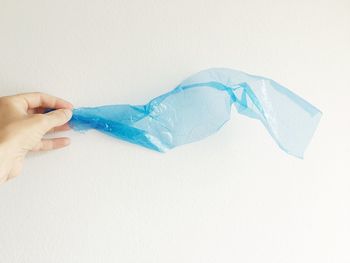 Close-up of hand holding paper over white background