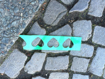 High angle view of heart shape paper on cobbled street