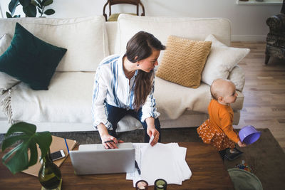 High angle view of mother calling playing daughter while working in living room at home office