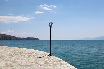 Street light by sea against sky