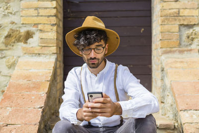Man wearing old-fashioned clothes using cell phone