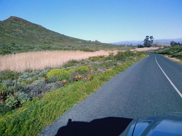 the way forward, road, clear sky, transportation, mountain, country road, landscape, diminishing perspective, tranquil scene, tranquility, vanishing point, grass, copy space, sky, road marking, blue, scenics, nature, mountain range, non-urban scene