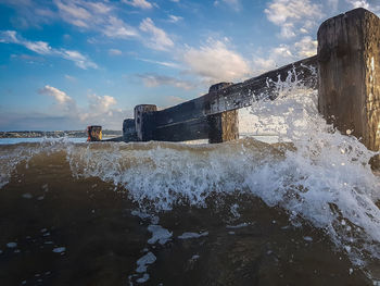 Waves splashing on shore against sky