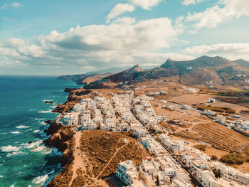 Aerial photo of naxos greece and white villas on a cliffside with mountains.