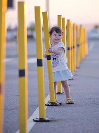 Cute girl standing by yellow poles on road