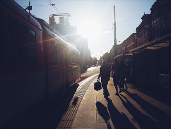 People on sidewalk by tram in city