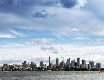 Sea by modern buildings against sky