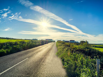 Road amidst agricultural field against sky