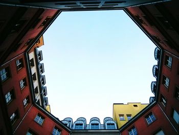 Low angle view of surrounded buildings against clear sky