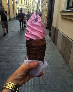 Midsection of woman holding ice cream cone on sidewalk