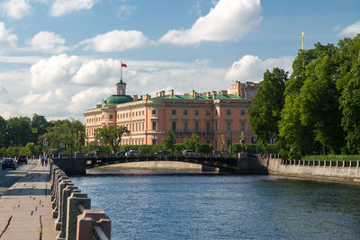 Buildings by river against sky