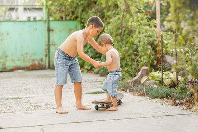 Siblings riding skateboard outdoors