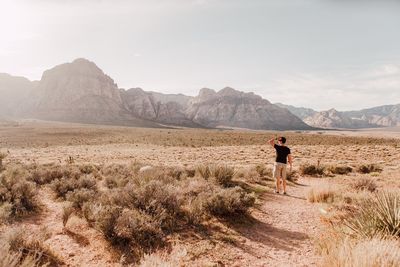 Rear view full length of man standing at desert against sky