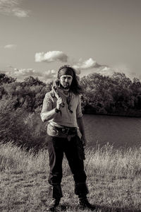 Portrait of man standing on field against sky