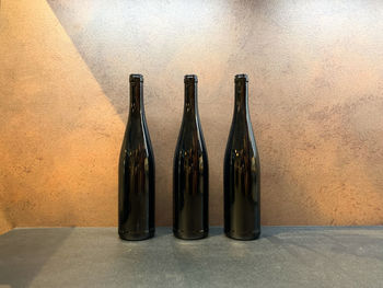 Close-up of empty bottles on table against wall