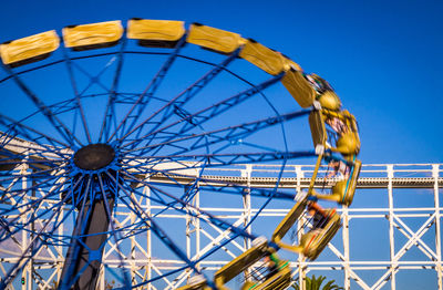 Low angle view of ferris wheel against clear blue sky