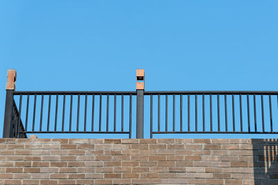 Low angle view of railing against clear blue sky