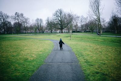 Rear view of child running on footpath in park