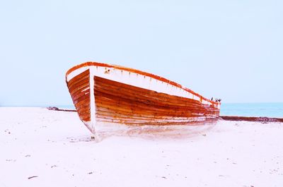 Abandoned boat on beach against clear sky