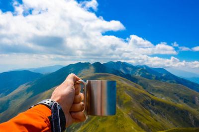 Close-up of hand holding mountain range against blue sky