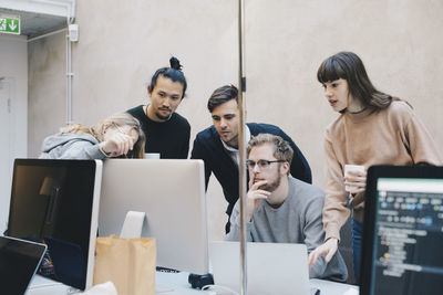 Young computer programmers using desktop pc at desk in creative office