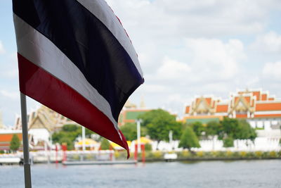 Low angle view of flag by river against buildings in city