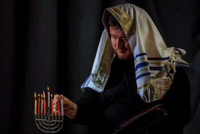 Close-up of priest igniting candles