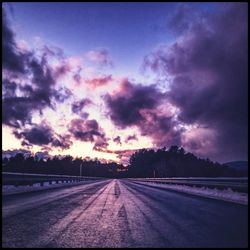 Empty road against dramatic sky during sunset