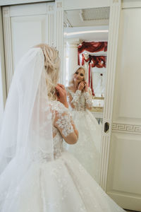 Reflection of bride getting dressed in mirror at home