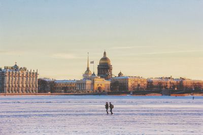 People on snow covered buildings against sky