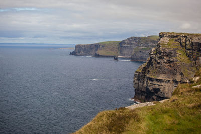 Scenic view of sea by cliff against sky