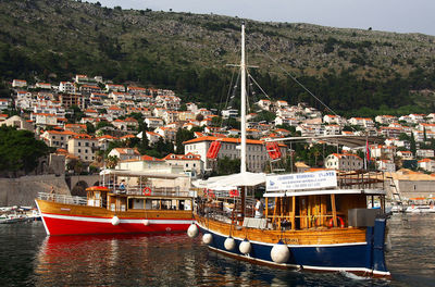 Boats moored at harbor against sky in city