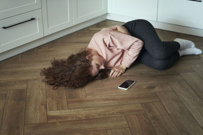 High angle view of woman sitting on hardwood floor