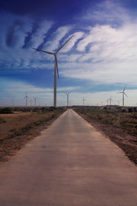 Dirt road amidst field against sky