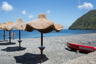 Deck chairs on beach against sky