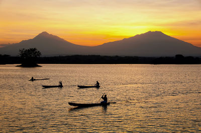 Silhouette boat in lake against sky during sunset