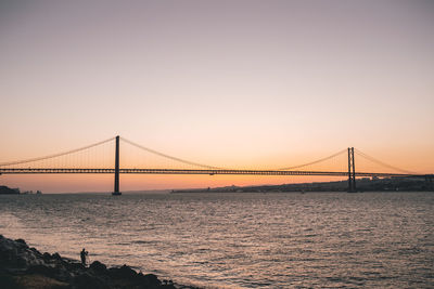 Bridge over sea against sky at sunset
