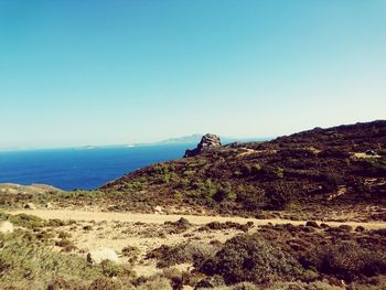 Scenic view of sea and mountains against clear blue sky