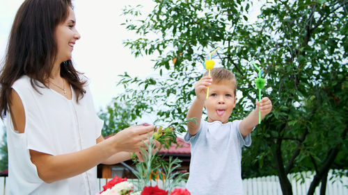 Summer, in the garden, slow motion, mom with a four-year-old son decorate the straw for juice. the