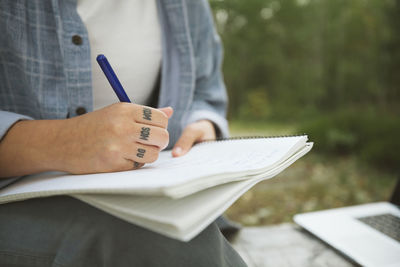 Young woman with notepad learning in forest