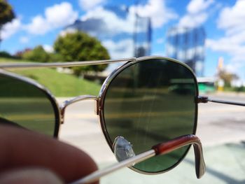 Close-up of sunglasses in city against sky
