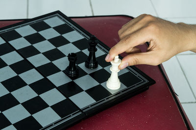 Cropped hand playing chess on table