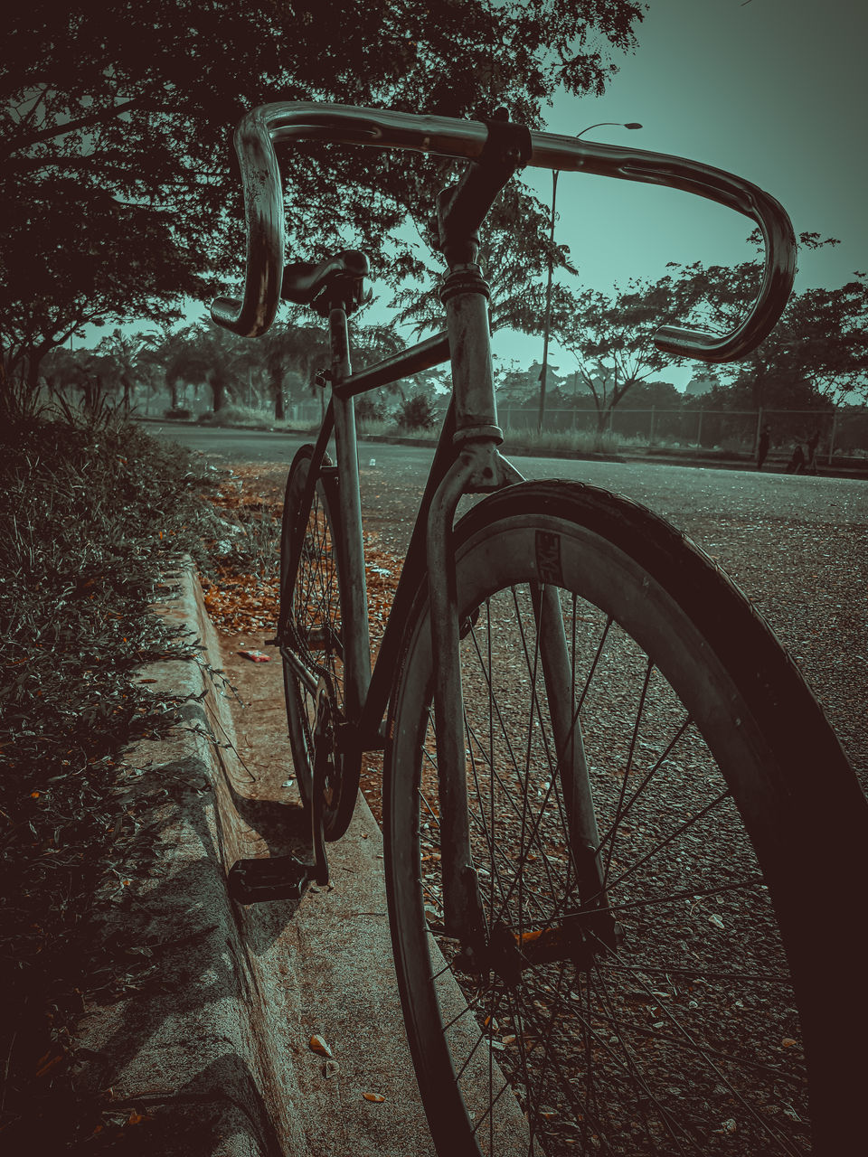 BICYCLE PARKED ON FOOTPATH BY ROAD